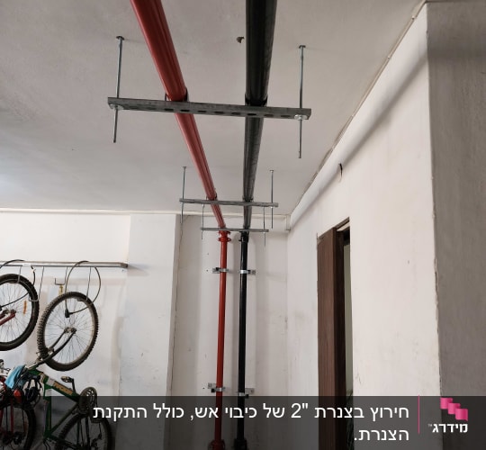 צינורות אדומים ושחורים מותקנים בתקרה, קשורים לכיבוי אש.